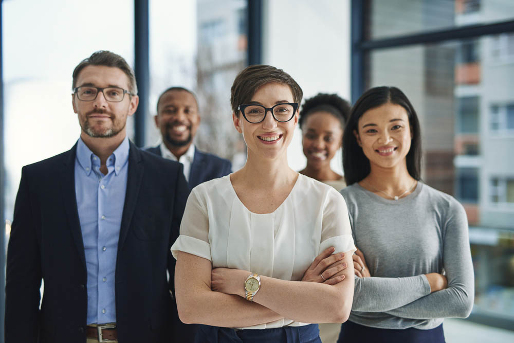 A proud, confident and diverse team of lawyers standing in an office or a law firm. Portrait of a happy and smiling group of advocates or legal employees in unity, teamwork and collaboration.